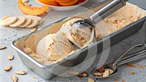 A sleek silver s emerges from a lidless container of soft peach ice cream mingling with a few lightly toasted almond photo