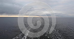 Sleek wake indignant streak of water remaining behind the stern of a going ship. Baltic Sea in cloudy weather.