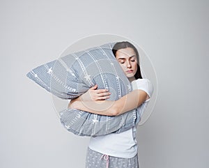 Sleep and drowsiness, a young woman hugs a pillow and sleeps standing up