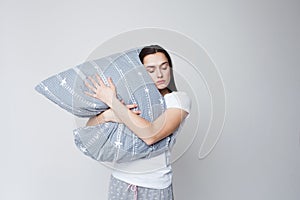 Sleep and drowsiness, a young woman hugs a pillow and sleeps standing up