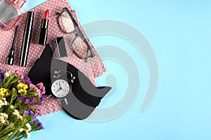 Sleep mask with alarm clock, flowers, mascara and pomade on blue background composition