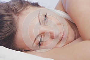 Sleep and rest after hard and successful work. Close up portrait young beautiful woman falls asleep in bed with smile on her lips