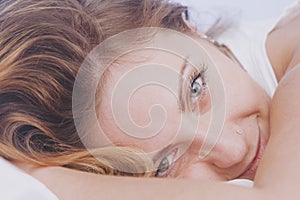 Sleep and rest after hard and successful work. Close up portrait young beautiful woman falls asleep in bed with smile on her lips