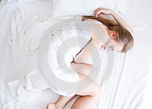 Sleep. Young woman sleeping in bed, female resting on comfortable bed with pillows in white bedding in light bedroom