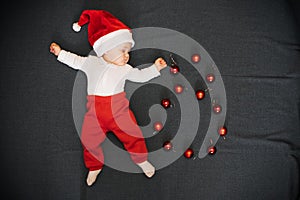 Sleeping baby boy with Santa hat lying with Christmas balls