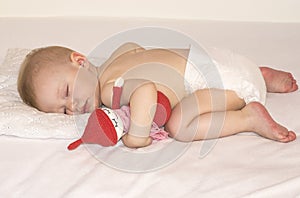 Sleeping baby in a diaper with a handmade toy