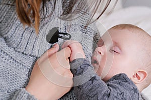 Sleeping baby gently holding mother`s finger