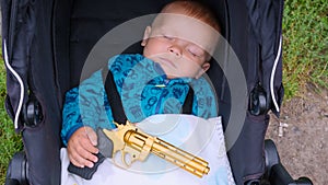 Sleeping baby with a gun in his hands