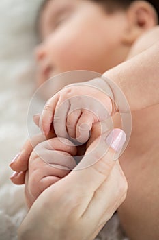 Sleeping baby holding mom`s finger