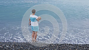 The sleeping baby in the Mom`s hands on the beach