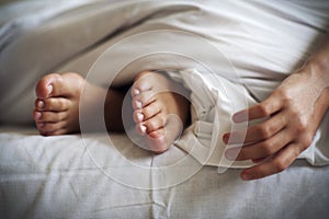 Sleeping child feet and hand on white bed linen