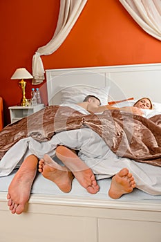 Sleeping couple barefoot bed side by side