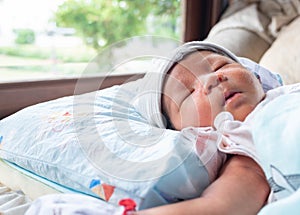 The Sleeping cute New Born Baby infant on the bed with a garden view from window