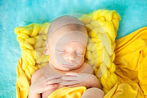 Sleeping cute newborn baby on a yellow chunky knit blanket