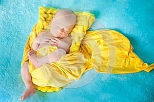 Sleeping cute newborn baby on a yellow chunky knit blanket