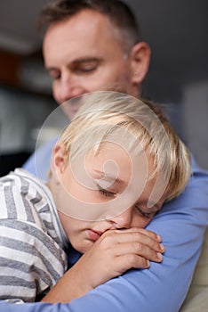 Sleeping on daddys shoulder. A mature father coming home from work and hugging his exhausted little boy.
