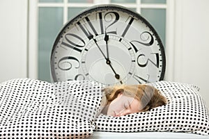 Sleeping girl in bed with alarm clock ,