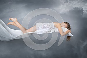 Sleeping girl. Flying in a dream. Clouds on grey background.