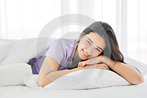 Sleeping girl smiling while lying down on the white bed on her comfy pillow in the morning