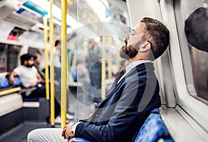 Sleeping hipster businessman inside the subway in the city, travelling to work.