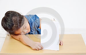 Sleeping little girl with book on the table.