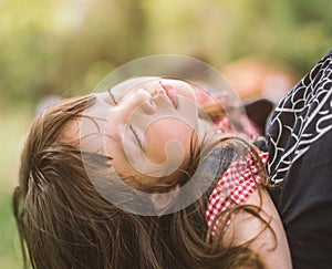 Sleeping little girl on mother shoulder in nature park.