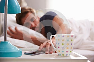 Sleeping Man Being Woken By Mobile Phone In Bedroom