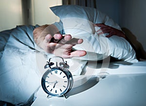 Sleeping man disturbed by alarm clock early mornin