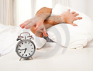 Sleeping man disturbed by alarm clock early mornin photo