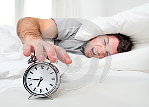 Sleeping man disturbed by alarm clock early mornin