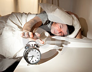 Sleeping man disturbed by alarm clock early mornin