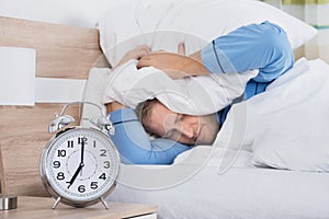 Sleeping Man Disturbed By Ringing Alarm Clock photo