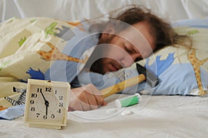 Funny sleeping man with hammer and headache pills and alarm clock in front of him