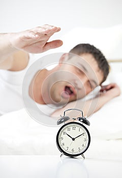 Sleeping man reaching for alarm clock