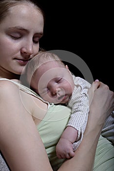 Sleeping mother with a sleeping baby on her chest, a moment of tenderness. Black background, space for text