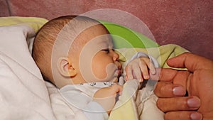 Sleeping Newbaby, infant. Father touches his son `s palm with his finger
