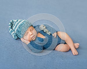 Sleeping newborn baby in blue jumpsuit and hat