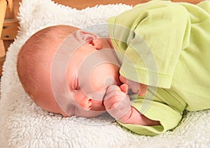 Sleeping newborn baby boy chewing his fist