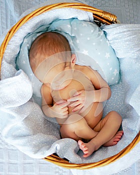 Sleeping newborn baby boy in wicker basket. Babyface close-up. Very sweet infant