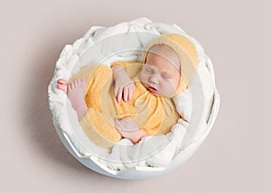 Sleeping newborn baby curled up on round basket