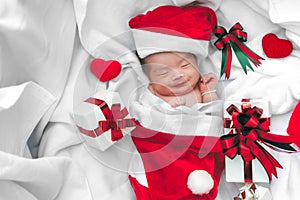 Sleeping newborn baby face in Christmas hat with gift box from S