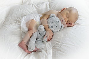 Sleeping newborn baby hugging a teddy bear photo