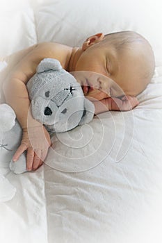 Sleeping newborn baby hugging a teddy bear photo