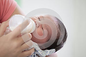 Sleeping newborn baby little girl drinking a milk from bottle