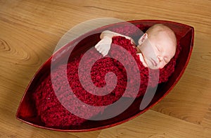 Sleeping newborn baby in red cocoon
