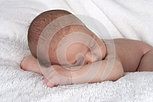 Sleeping newborn baby resting head on arms