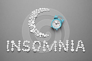 Sleeping pills and an alarm clock, insomnia concept. Medications for fatigue and sleep problems