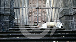 Sleeping rough homeless on the stairs of the building in front of the gate