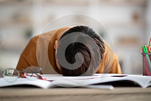 Sleeping schooler laying on desk full of exercise books