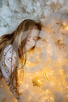 Sleeping sleeping sweet girl with long hair in fluffy white fluff and magic lights.